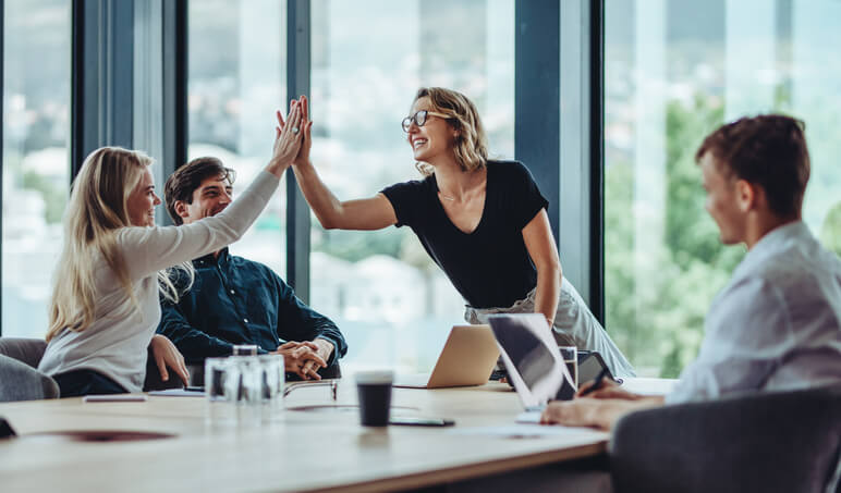 An entrepreneur giving a high-five to her teammate during a brainstorming session after business administration training