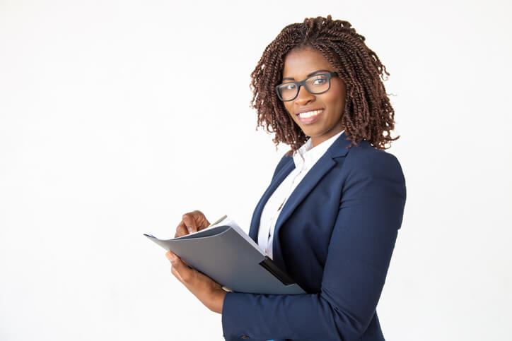 A smiling female legal assistant holding a notepad after legal assistant training