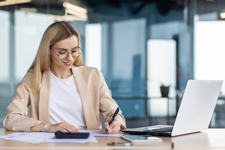 A smiling female accounting clerk writing a report in an office after accounting training