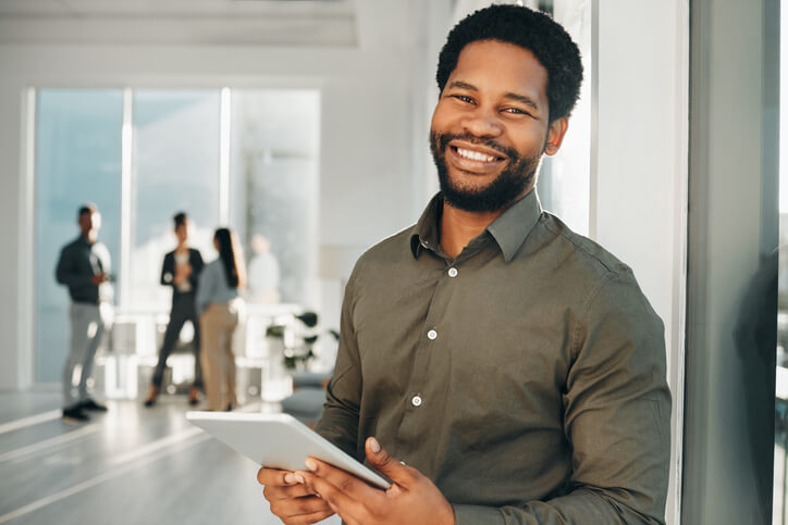 A male business administration training graduate holding a tablet in an office
