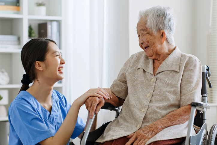 A cheerful female home support worker interacting with a smiling elderly female patient