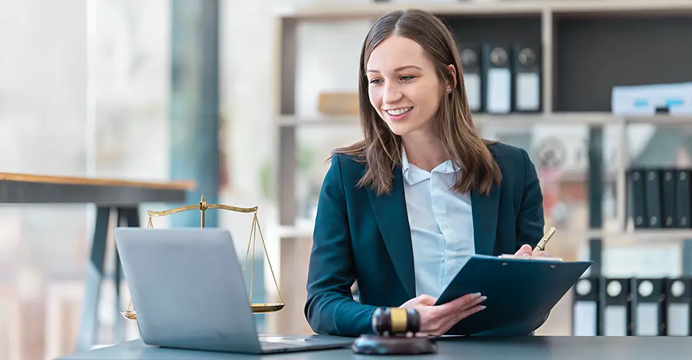 Legal assistant taking detailed notes on her laptop while working in a law firm.