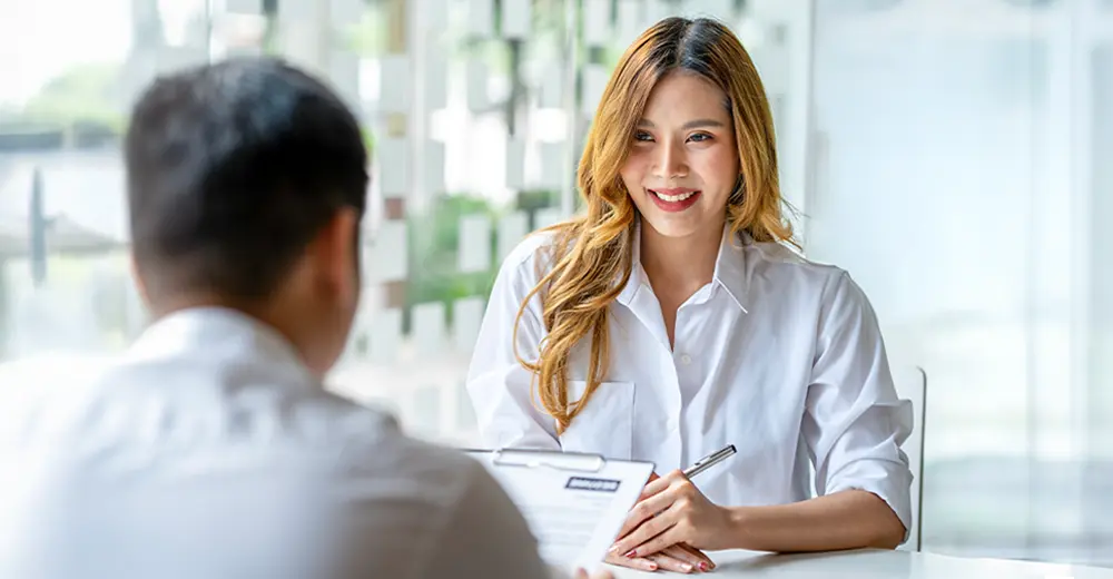 A business graduate smiling during a job interview with a hiring manager.